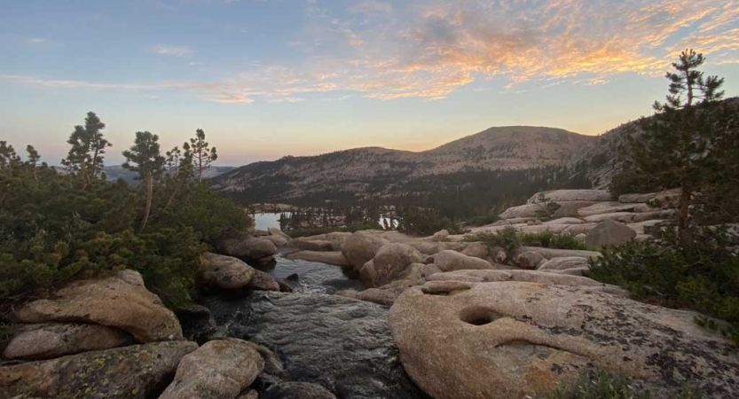 A stream passes through rocks and boulders in a mountainous landscape.